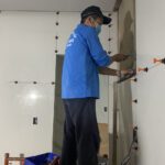 Thợ thi công đang sử dụng ke cân bằng để ốp gạch tường phẳng tắp.