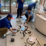 Đội ngũ thợ đang ghép tranh đá hoa văn cổ điển trên nền sàn.